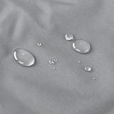 Close-up of a light gray textured fabric surface with several clear water droplets showing water repellency.