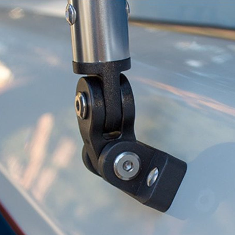 Close-up of a black metal mounting bracket attached to a silver cylindrical pole, shown against a blurred light gray surface.