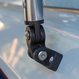 Close-up of a black metal mounting bracket attached to a silver cylindrical pole, shown against a blurred light gray surface.